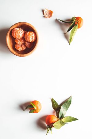 beautiful ripe tangerines with green leaves on wooden plateの写真素材