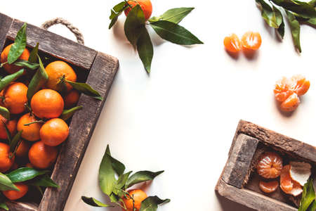 tangerines with fresh leaves in wooden box isolated on white, isolated on a white, top viewの写真素材