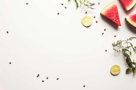 Red slices of ripe watermelon with mint leaves and lime slices on a white background.の写真素材