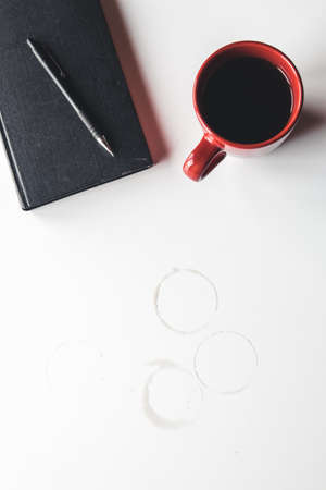 Blank organizer with pen and empty and full red coffee cups. Isolated on white backgroundの写真素材