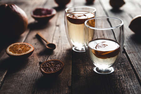 Citrus tea in a transparent teapot and a glass, healthy drink on a wooden background.の写真素材