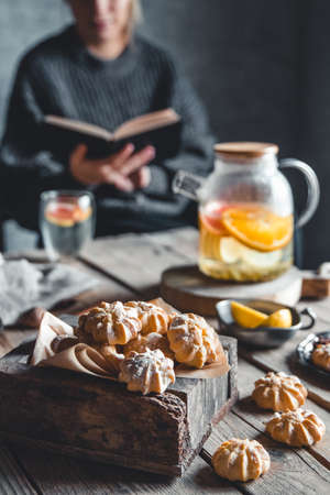 Woman is reading and Hot tea with fresh grapefruit on wooden tablet. Healthy drink, Eco, vegan.の写真素材