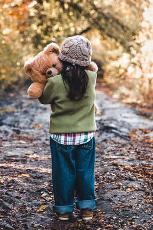 Little girl hugs her bear on a background of nature, autumn, durba.の写真素材