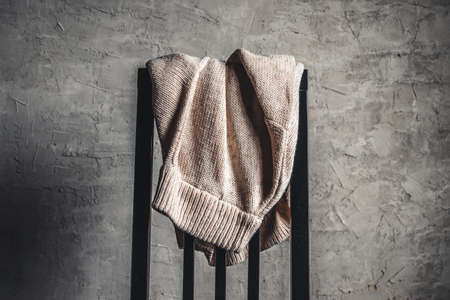 Knitted beige sweater on the back of a white wooden chairの写真素材