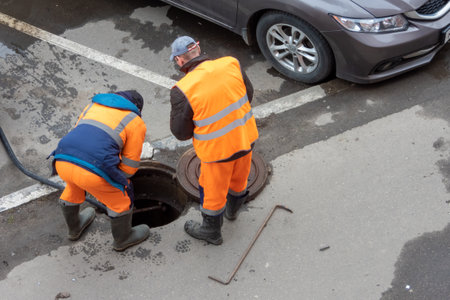 Workers over the open sewer hatch on a streetのeditorial素材
