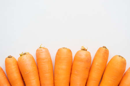Ripe carrots laid out in a semicircle on a light beige backgroundの写真素材