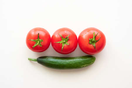 Three ripe tomatoes and one green cucumberの写真素材