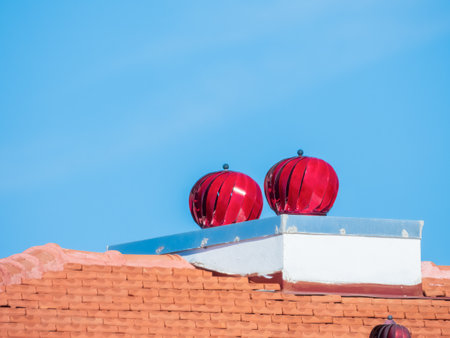 Red colored turbine vents on the roof, against a blue skyの写真素材