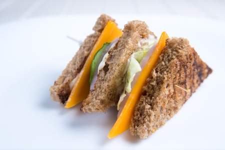 A sandwich with toasted bread, cheese, cucumber, lettuce and ham on a skewer. Italian cuisineの写真素材
