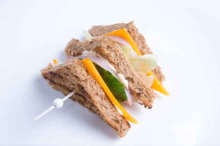 A sandwich with toasted bread, cheese, cucumber, lettuce and ham on a skewer. Italian cuisineの写真素材