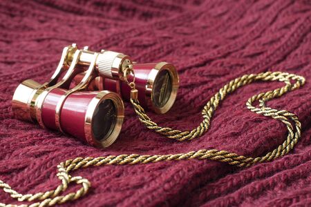 vintage red theater binoculars on the background of a knitted burgundy scarf