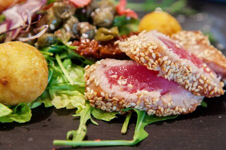Salad of tuna in sesame with arugula, dried tomatoes, capers and balls of potatoes. original feed.の写真素材