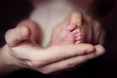 Leg of a newborn in dad's handの写真素材
