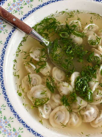 Dumplings with broth served in a beautiful plate with ornaments and sprinkled with herbs. Spoon in a plate.の写真素材