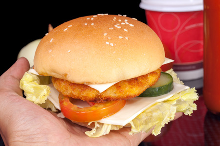 Hand giving Big Homemade Cheese Chicken Burgerの写真素材