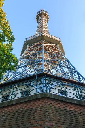 Historical observation tower and former metal radio tower on Petrin hill in Czech capital Prague. Masonry base in the evening with blue skies and trees in the evening sunの写真素材