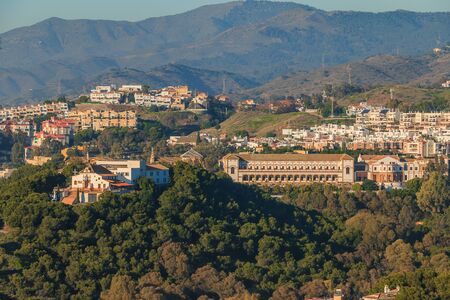 Panoramic view in Malaga from the hill of the Barcenillas district with Sagrada Familia El Monte. Hills with forest, trees, and apartment buildings on a sunny day. University with buildingsの写真素材