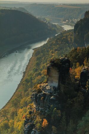 River Elbe in Saxon Switzerland in autumn mood. Rocks with stones and forests in the sunshine. Boat on the river in the Elbe valley. Trees in seasonal colorsの写真素材