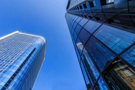 Between two skyscrapers. Looking up at buildings in Frankfurt. blue window front from the skyscraper in sunshine and blue sky. Commercial buildings in the city centerの写真素材