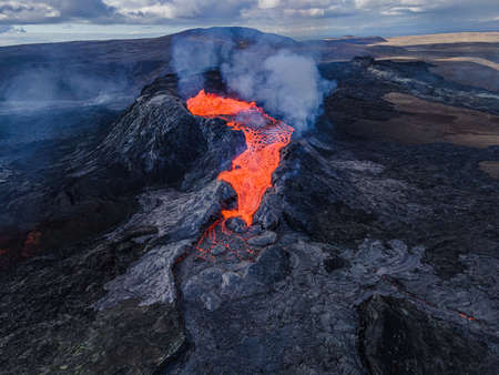 Lava flow from the crater opening of Fagradalsfjall volcano. View from above into the volcanic crater on Iceland in the GeoPark. Daytime volcanic eruption on Reykjanes peninsula.の写真素材