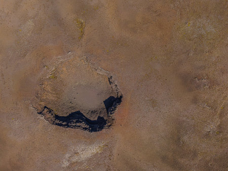 Old crater from above in sunshine. View into an extinct crater on Iceland Rekjaney Peninsula. landscape of brown sand around the crater. Shadows cast by cratersの写真素材