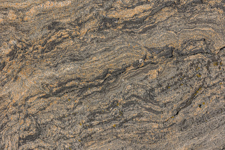 Granite structure with wavy lines and small line breaks. Background pattern natural stone with brown gradient. light and dark spots in the stone due to weatheringの写真素材