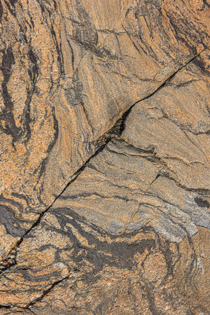 Coarse wave pattern in brown granite stone. Background pattern of natural stone. Diagonal structural break in the surface. Isolated gray and dark areas in the patternの写真素材