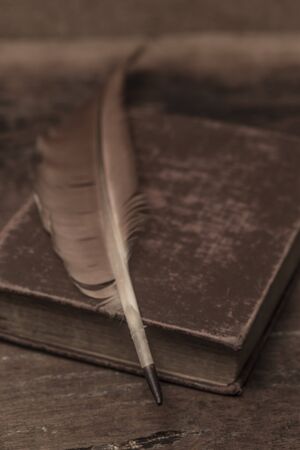 Vintage old books, scrolls, feather pen and inkwell on wooden tableの写真素材