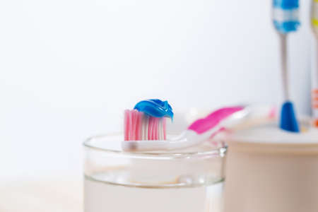 Toothbrushes on a glass with water on a wooden table.の写真素材