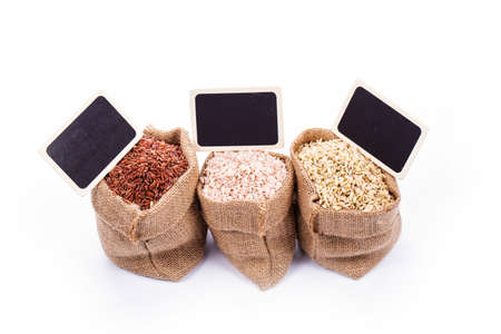 unpolished rice (whole grain) in a burlap bag on a white backgroundの写真素材