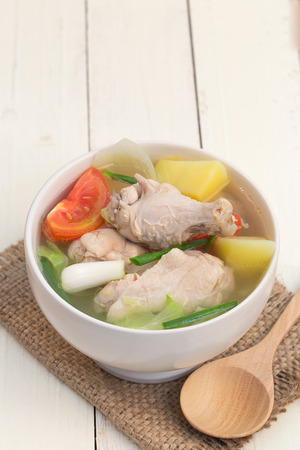 Chicken soup with vegetables on a white wooden table.の写真素材