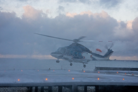 Passenger helicopter in the snow blizzard taking off from the platform at bad snow storm weatherの写真素材