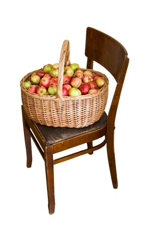 An isolated picture of basket full of colorful apples on an old chairの写真素材
