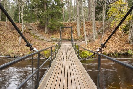 Chain bridge over river in forestの写真素材