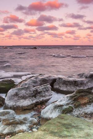 Icy stones near sea coast at sunsetの写真素材