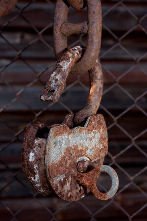 Big old rusty metal open padlock with a key hanging on a bold chainの写真素材