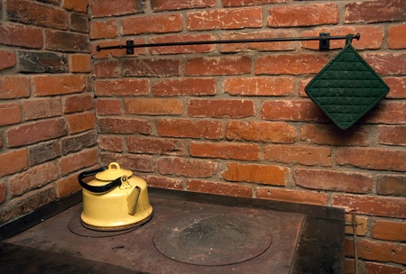 Yellow tea pot on a stove, red brick wall in backgroundの写真素材