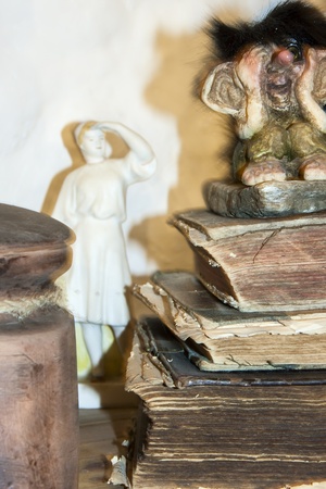 A troll is sitting on very old books next to female sculptureの写真素材