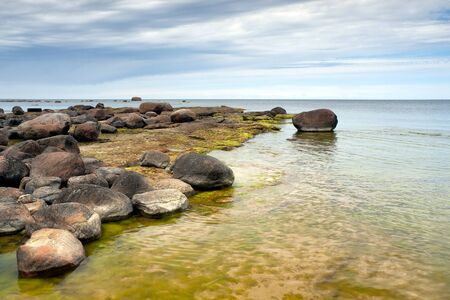 Seashore with a lot of rocks at cloudy overcast dayの写真素材
