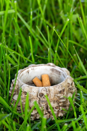 Ashtray with cigarette ends on green grassの写真素材