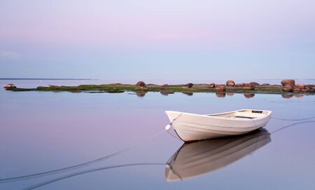 White boat tied up with ropes  in sea at sunsetの写真素材