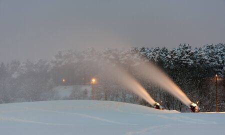 Illuminated snow cannons making and blowing snow in the winter evening の写真素材