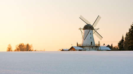 Old white stone made windmill behind snow fieldの写真素材