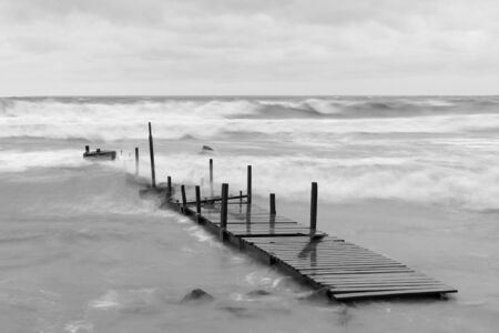 Wooden bridge in a stormy and wavy seaの写真素材