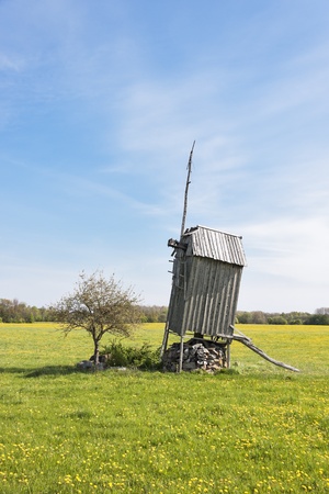 Old abandoned wooden windmill on grass field in Saaremaa, Estonia の写真素材