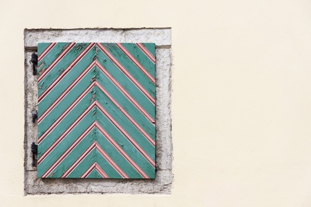 Old striped green hatch surrounded by limestone border in yellow wallの写真素材