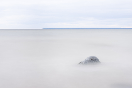 Single stone or rock in a blurry sea, isle on background at horizonの写真素材