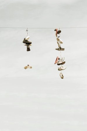 Many old worn boots or shoes hang on an electric cableの写真素材
