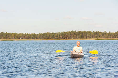 Man in yellow t-shirt drive canoe or kayak in a lake or seaの写真素材