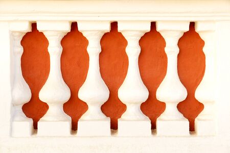 Closeup of white architectural columns in front of red background